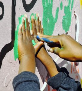 A painted hand helps press smaller hands to make a hand print on the Mason Lincoln mural
