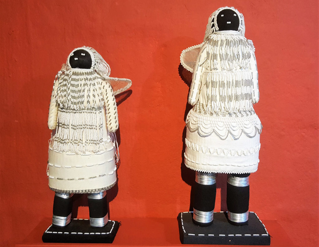 61. Art White Angel Dollsby Tholiwe Sithole that tell everyone about good behaviour; Two dolls one larger than wearing fringed white dresses with wings.
